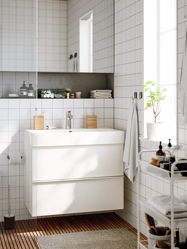sundrenched浴室用白色瓷砖,猛然站起身,两个抽屉和一个HORNAVAN电车和浴室配件。