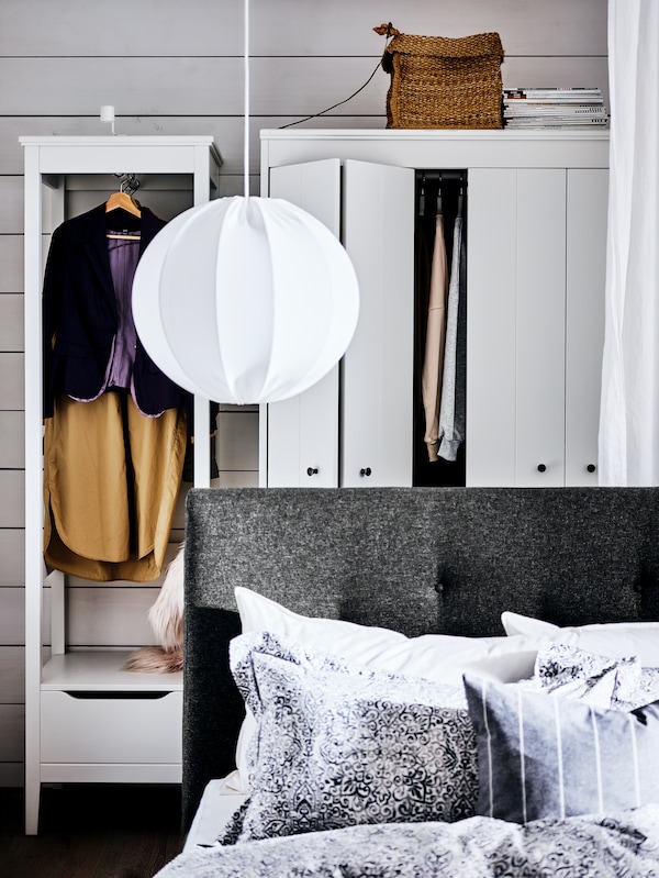 灰色IDANAS软垫床吊灯上面,前面的两个白色衣柜挂衣服。