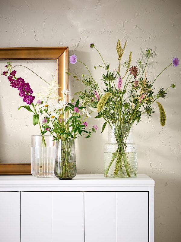 白色的内阁与五颜六色的花朵上,分为两个不同的GRADVIS玻璃花瓶和一个KONSTFULL花瓶。