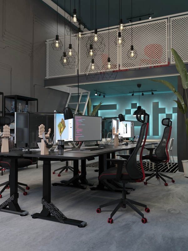 四个黑色UPPSPEL游戏桌子和四个MATCHSPEL游戏在游戏开发的办公室椅子和高高的天花板。