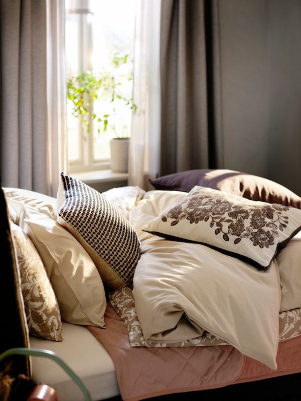 床的顶部覆盖着的混合物neutral-coloured ANGSLILJA VARBRACKA床上纺织品和SKUGGNAVA缓冲。