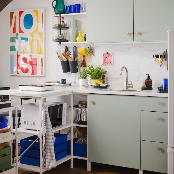 厨房与存储ENHET门在浅灰绿,ENHET墙框架与货架上白色和彩色海报。