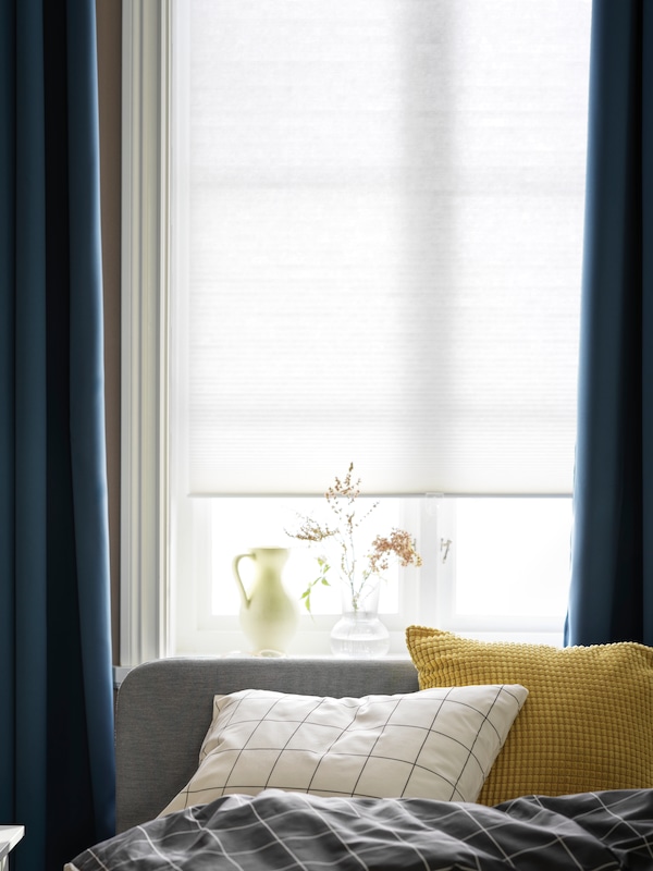 床头旁边的一个窗口,窗口处理HOPPVALS细胞组成的盲目和HILLEBORG窗帘。
