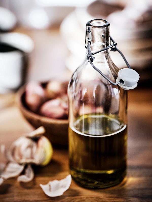在木塞的玻璃瓶表面,装用橄榄油,旁边一碗大蒜鳞茎。