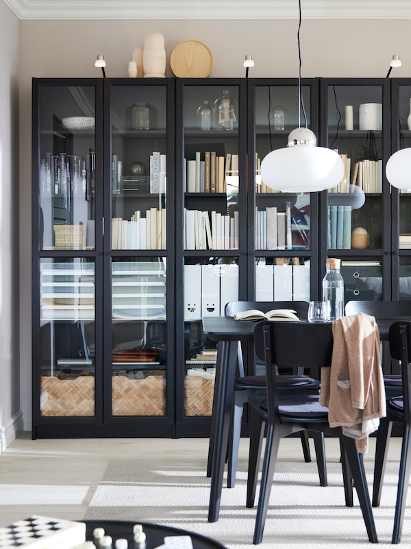 三个黑人比利/ OXBERG书架玻璃门沿着墙背后的餐桌,椅子和两个吊灯。