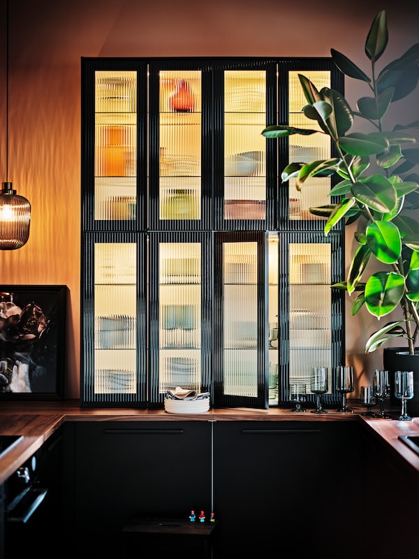 厨房用无烟煤/条纹玻璃大门上面一个工作台。一个吊灯照亮空间。