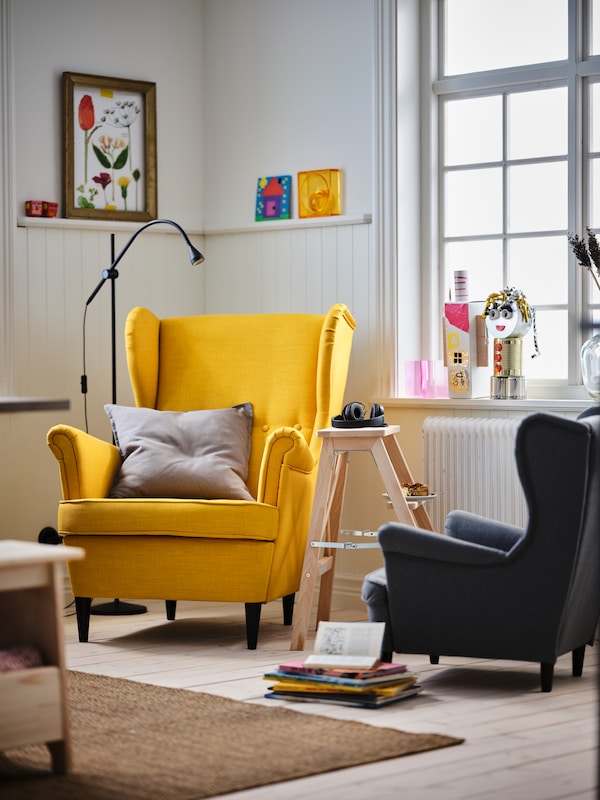客厅角落里的黄色STRANDMON翼把椅子和一个灰色STRANDMON儿童扶手椅。