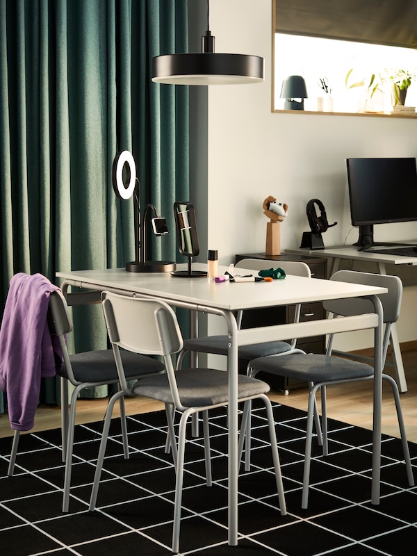一套灰色GRASALA餐厅有四把椅子在一间小公寓里与美容产品放在桌子上。