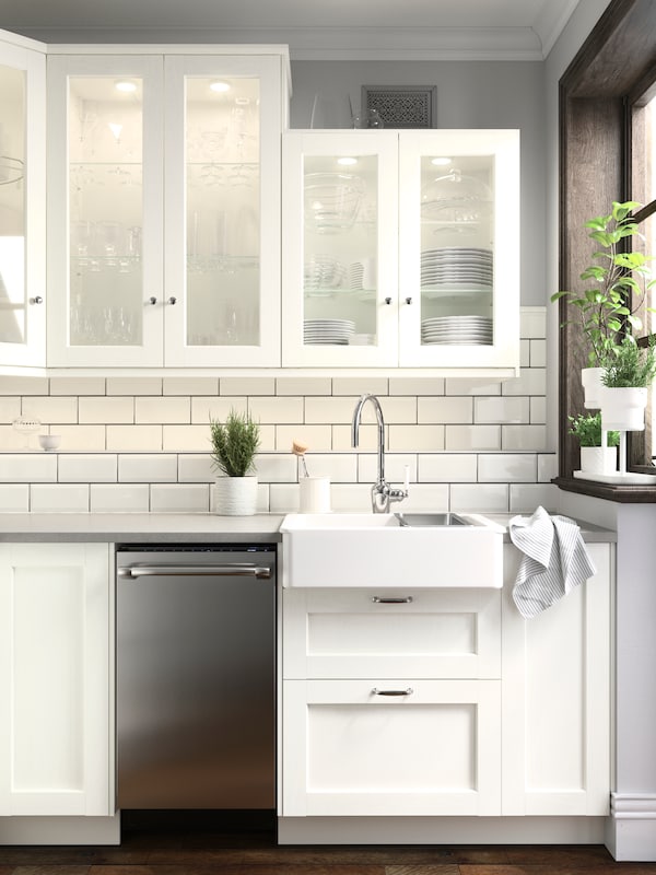 SEKTION厨房白色的瓷砖墙和ENKOPING厨房方面在白色和白色的墙柜和一些绿色植物。