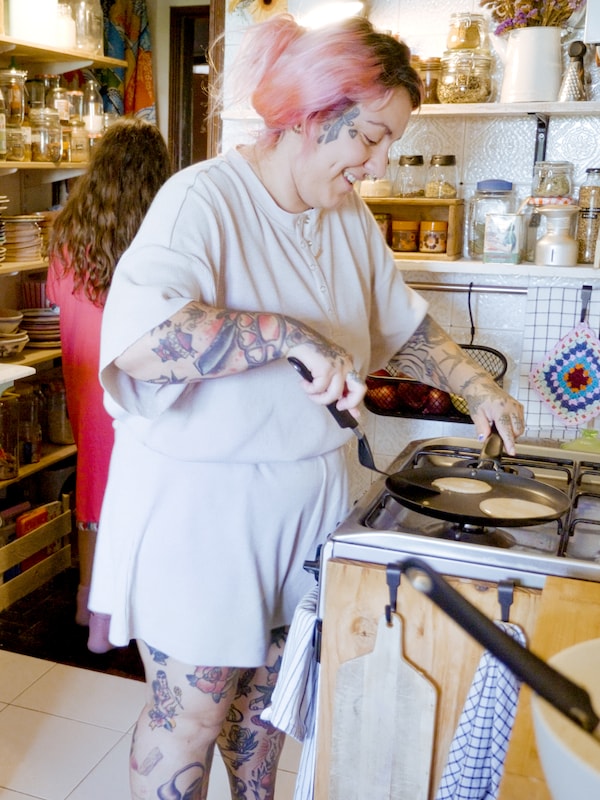 一个微笑的女人是在做煎饼HEMLAGAD煎饼锅炉子上。