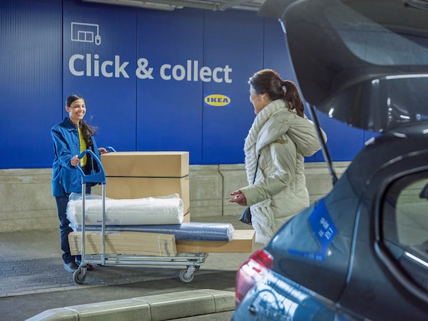 Eine 亚博平台信誉怎么样IKEA Mitarbeiterin übergibt einer Kundin einen Wagen mit mehren Paketen bei der Click & Collect Abholstation。