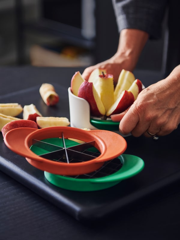 一些UPPFYLLD水果刀具在一组四个混合颜色,一个人的手切水果切一个苹果。