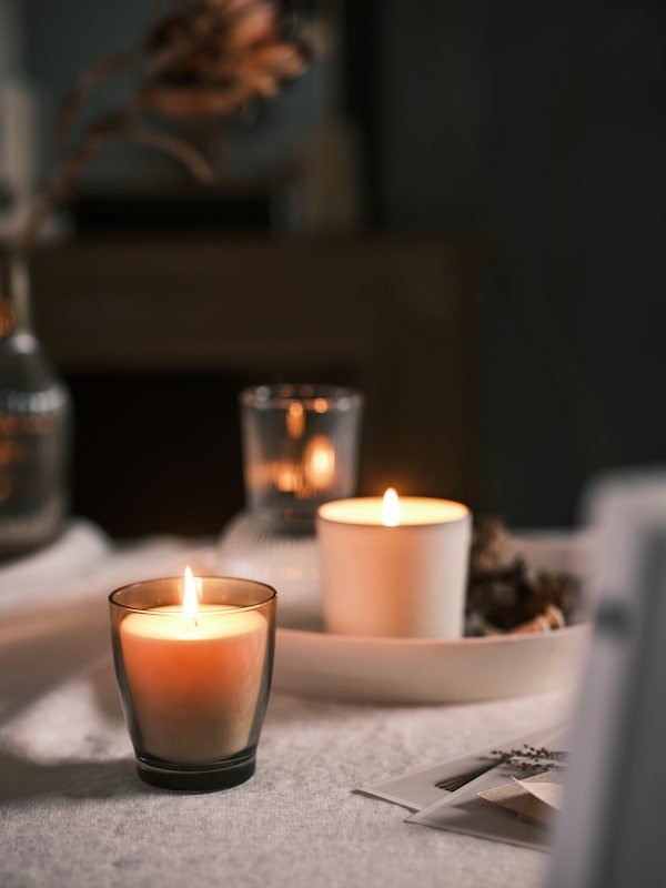 灰色ENSTAKA带香味的蜡烛,一个白色ADLAD香味蜡烛,装饰和白色的托盘,放在桌布上。