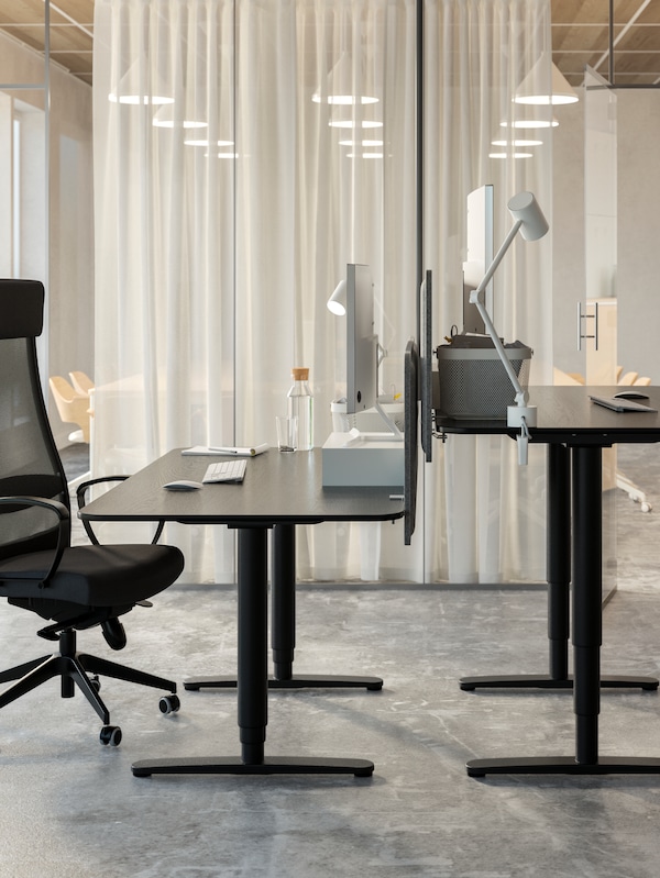 两个高度不同,面临black-stained-ash-veneer-and-black BEKANT坐立办公室室内桌子站在一盏灯。