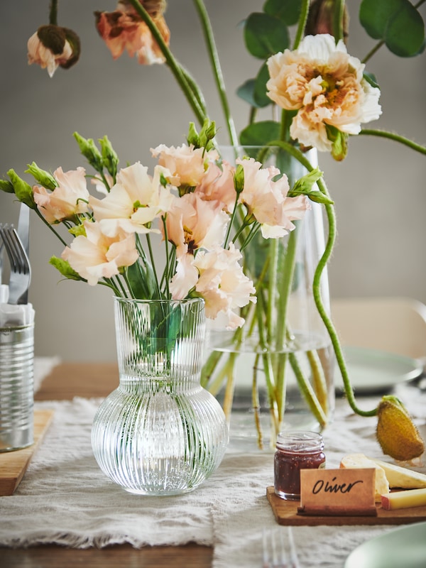 粉红色的降低在透明玻璃花瓶PADRAG放在桌上。有一个小标志与名称奥利弗。