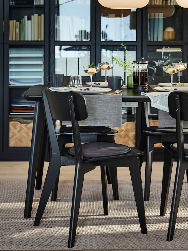 两个黑LISABO餐厅的椅子在桌子前与盘子,碗,香槟轿跑车和表跑步者。