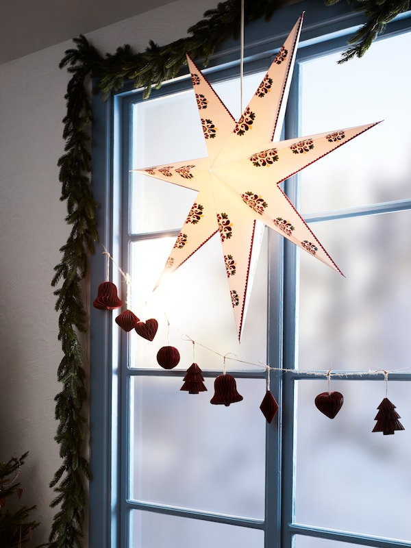 一个STRALA星形灯罩与VINTERFINT挂装饰品挂在一个窗口。领导花环STRALA帧窗口。