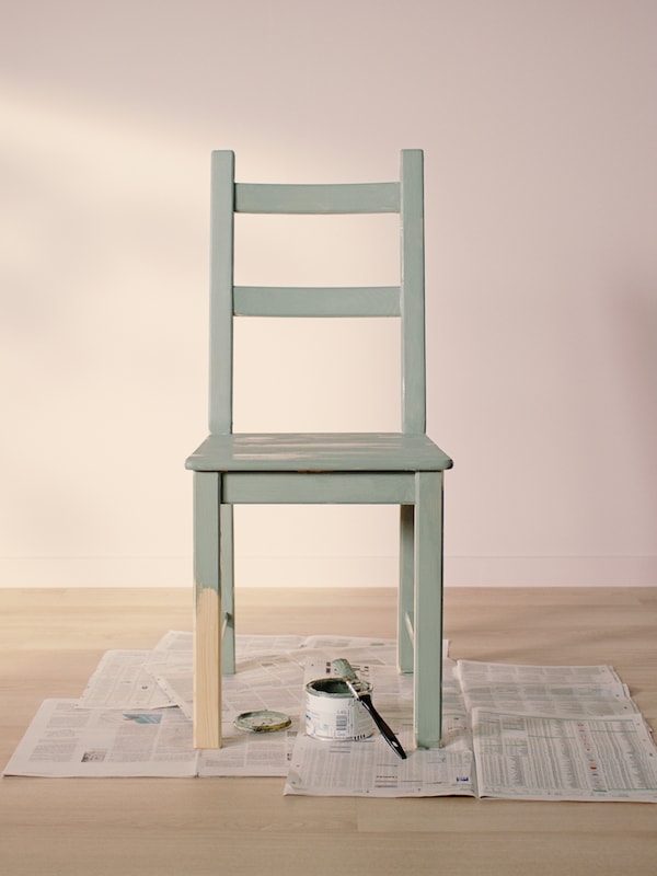 IVAR松树的椅子,漆成绿色除了一半的一条腿,站在报纸上一罐颜料和画笔。