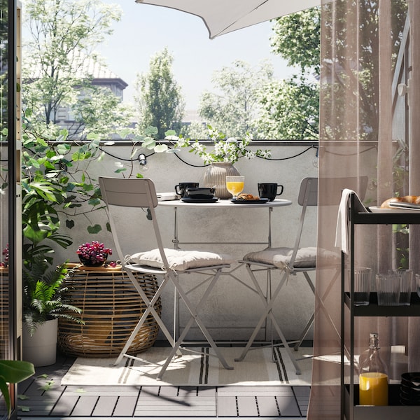 一个阳台和一个灰色SUNDSO户外表和两个灰色的户外椅子在地毯,加上一张咖啡桌,植物和阳伞。