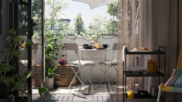 一个阳台和一个灰色SUNDSO户外表和两个灰色的户外椅子在地毯,加上一张咖啡桌,植物和阳伞。