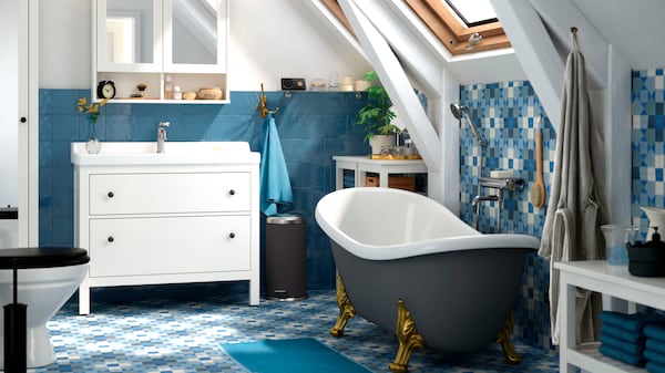 与蓝色地板和墙壁瓷砖浴室,独立的浴缸,白色洗手盆橱柜上面反映出来。