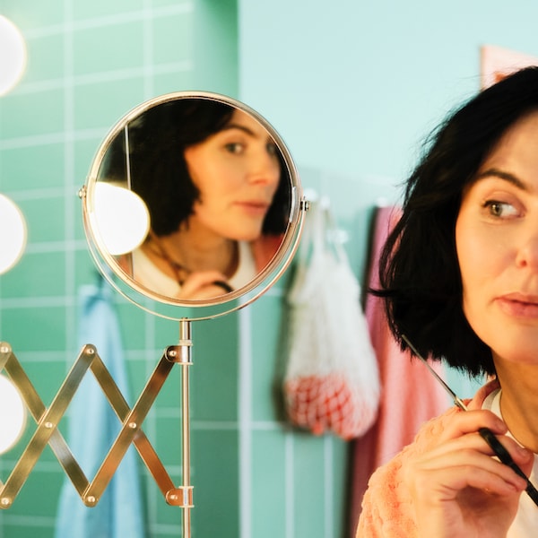 与绿色瓷砖浴室,一个女人正在调查一个液压镜子剪自己的头发。