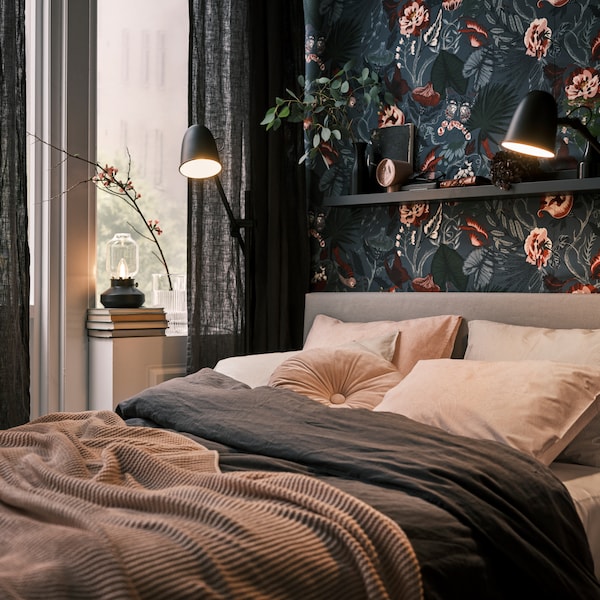 一张床在一个黑暗的,植物的墙,用黑色SKURUP地板/阅读灯两边,加上TARNABY台灯在窗口。