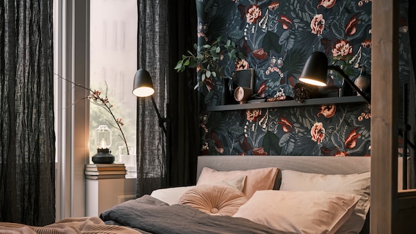 一张床在一个黑暗的,植物的墙,用黑色SKURUP地板/阅读灯两边,加上TARNABY台灯在窗口。