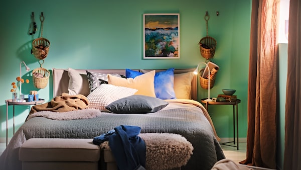 床上用白色/米色KLEPPSTAD床框架由灰绿色的床罩和各种垫子,加上两个托盘表。