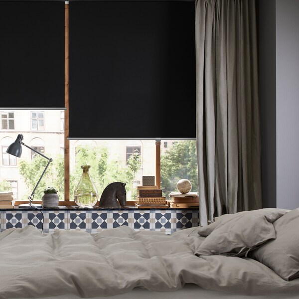 一间卧室和一张床在中间灰色的窗帘和窗户TRETUR阻挡卷帘的一半。