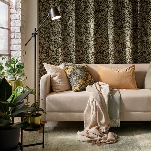 浅褐色LINANAS光灰绿色的地毯沙发与各种靠垫,前面的树叶图案的窗帘挂在墙上。
