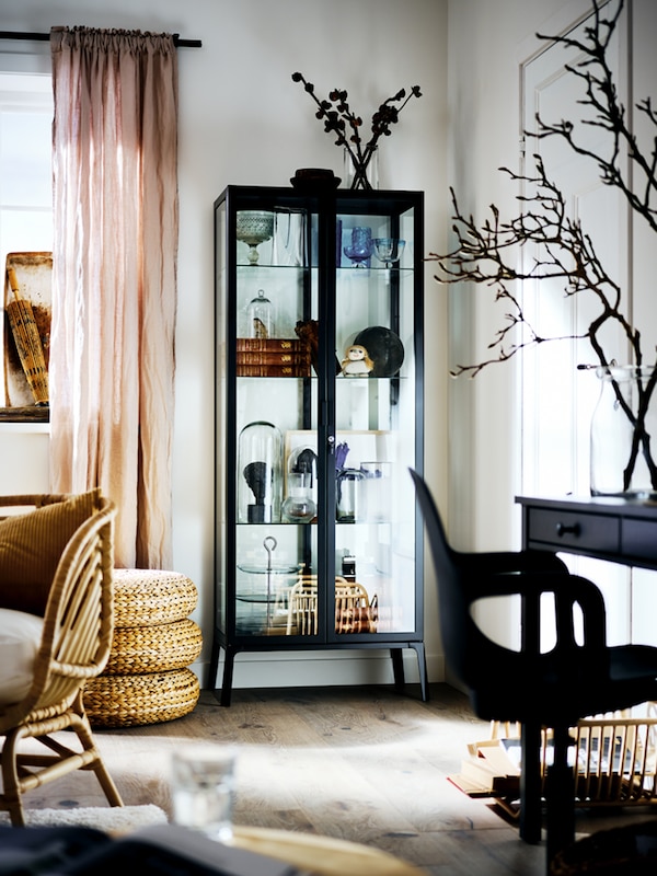 黑色MILSBO内阁玻璃门,里面填满了各式各样的对象,一个明亮的客厅的角落里。