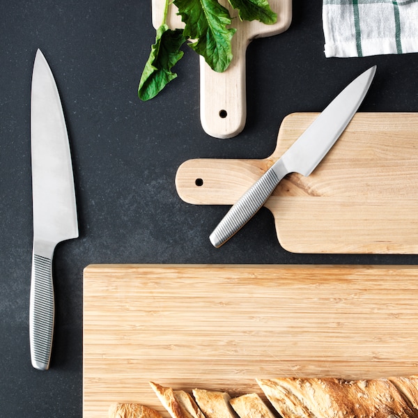 黑色表面三个木砧板和两个厨房刀具。一块面包是一个切菜板。