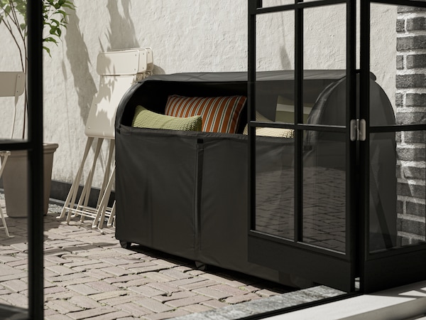 黑色TOSTERO户外存储箱缓冲存储在它代表对墙在一个阳光明媚的户外空间。