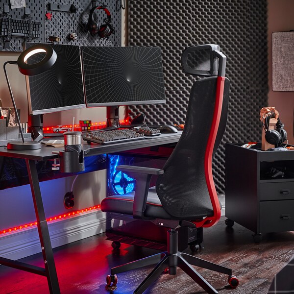 黑色UTESPELARE游戏桌上有两个屏幕,一个黑色的游戏的椅子上,一个黑色的抽屉单元和各种游戏配件。