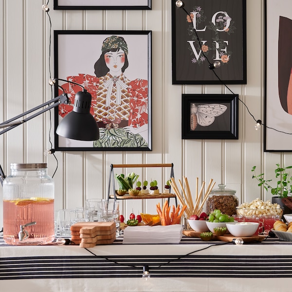 自助餐表与食品和饮料在各碗,盘子和VARDAGEN jar的自来水,一堵墙在帧图片。