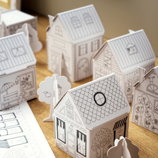 儿童玩具玛拉纸板小镇不同的房屋和树木,放置在一个木制的表面。