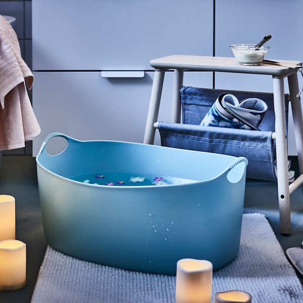 一个舒适的卫生间设置蓝色TORKIS洗衣篮装满水在地板上,周围放置了蜡烛。