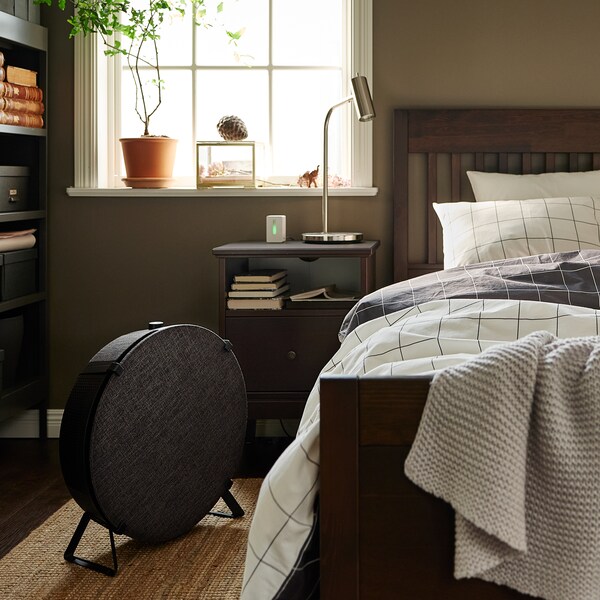 一个深棕色IDANAS床上检查VITKLOVER床单上自然LOHALS flatwoven地毯,加上一个圆形黑色的空气净化器。