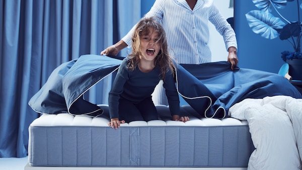 女孩在蓝色的睡衣在浅蓝色VALEVAG口袋里装有弹簧床垫和一个人摇蓝表在她的身后。