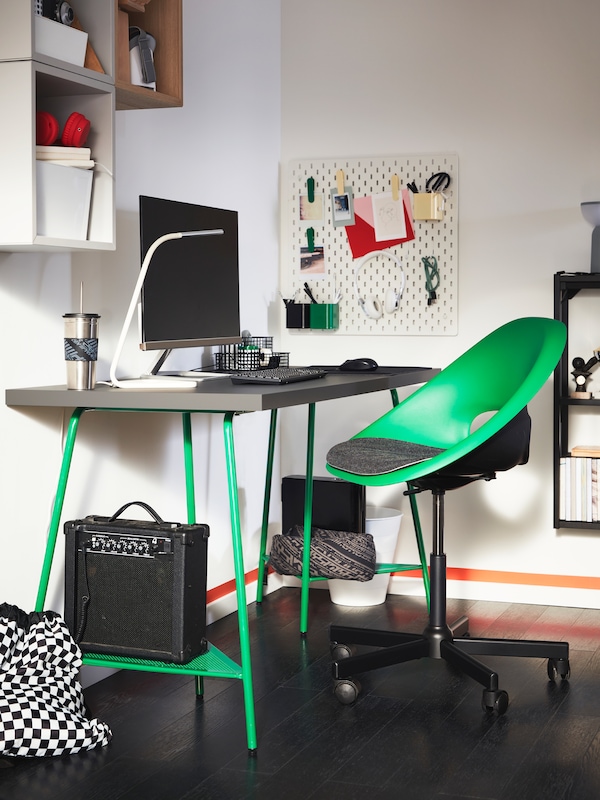 灰色的LAGKAPTEN桌面，绿色的TILLSLAG支架和前面的绿色转椅。显示器在桌子上。