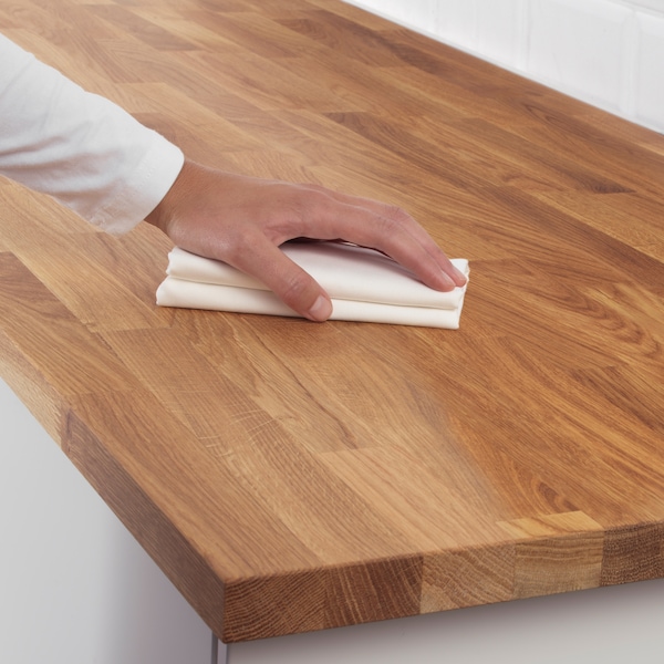 一只手拿着白色清洁布的表面木制厨房工作台。
