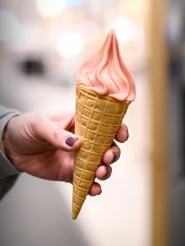 一只手一个人穿着一件灰色上衣和紫色指甲油持有满草莓冰淇淋筒软冰。