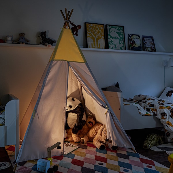 HOVLIG帐篷里面有各种动物毛绒玩具和一盏灯,在黑暗的房间里两个BUSUNGE可扩展的床。