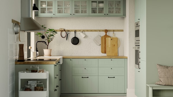 厨房STENSUND浅绿色方面,GRUNDAD感应滚刀在黑色和壁挂式MATTRADITION器罩。