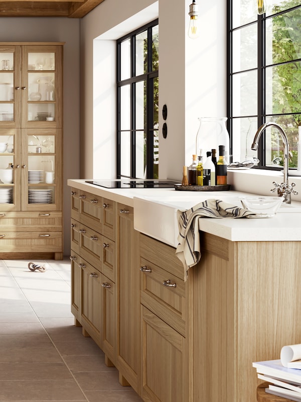 一个大型的、明亮的厨房与橡木VEDHAMN方面,包括玻璃门柜装满玻璃器皿和餐具。