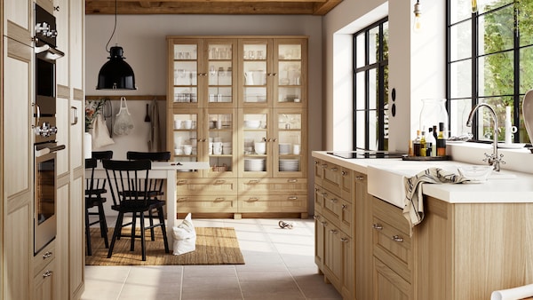 一个大型的、明亮的厨房与橡木VEDHAMN方面,包括玻璃门柜装满玻璃器皿和餐具。