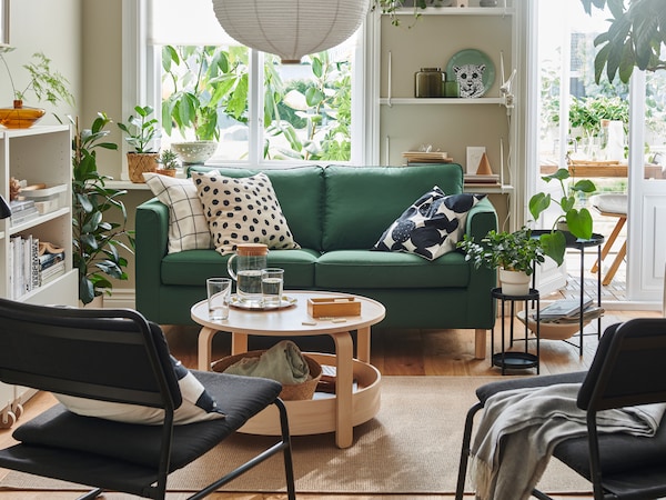 客厅光线由一个深绿色PARUP双座沙发,graphic-pattern纺织品、木材的口音和绿叶植物。