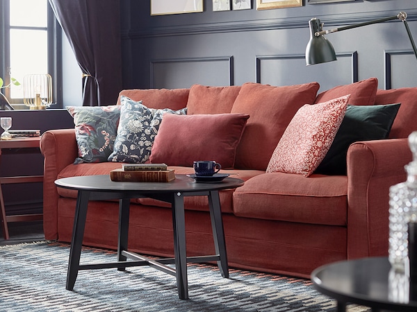浅红色GRONLID 3三种座位沙发与图案的靠垫,黑咖啡桌在一个传统风格的客厅。