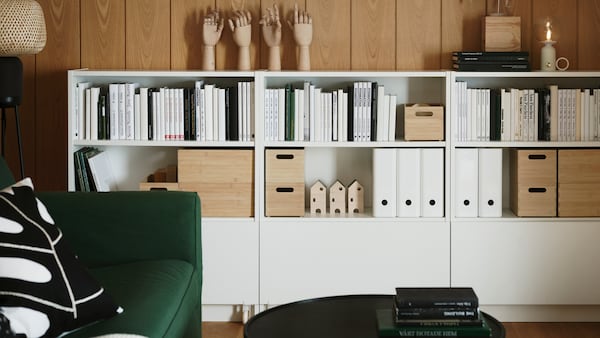 客厅有一连串白色比利一侧墙壁的书架,书架上有书和文件夹整齐地组织。